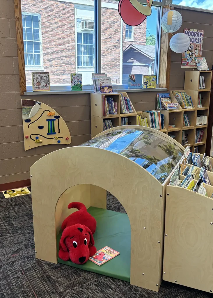 stuffed dog in a book shelf shaped like a dog house